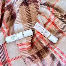 Load image into Gallery viewer, Two lip balm tubes on a plaid fabric background