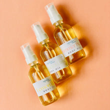 Load image into Gallery viewer, Three bottles of body oil on a peach background